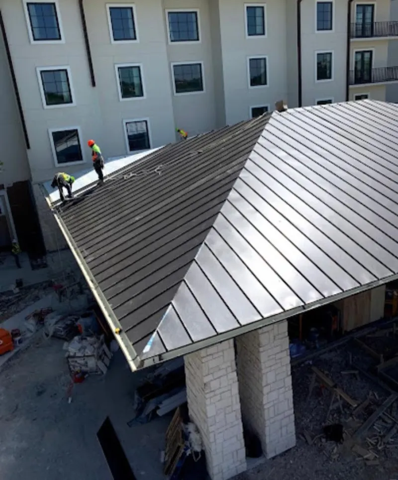 Crew installing standing seam metal roof panels on a commercial project in Whiskey Creek